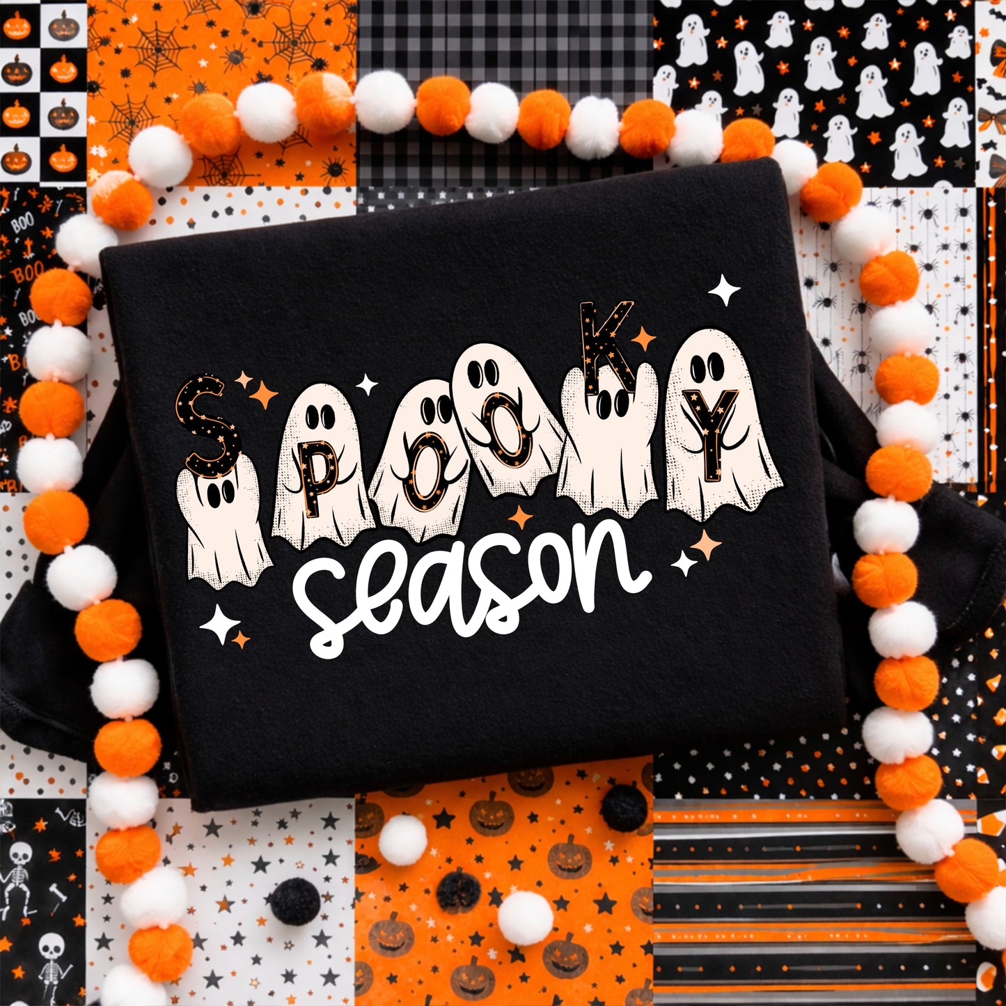 Woman wearing a black Spooky Season Halloween graphic T-shirt featuring cute white ghosts, orange stars and retro lettering.
