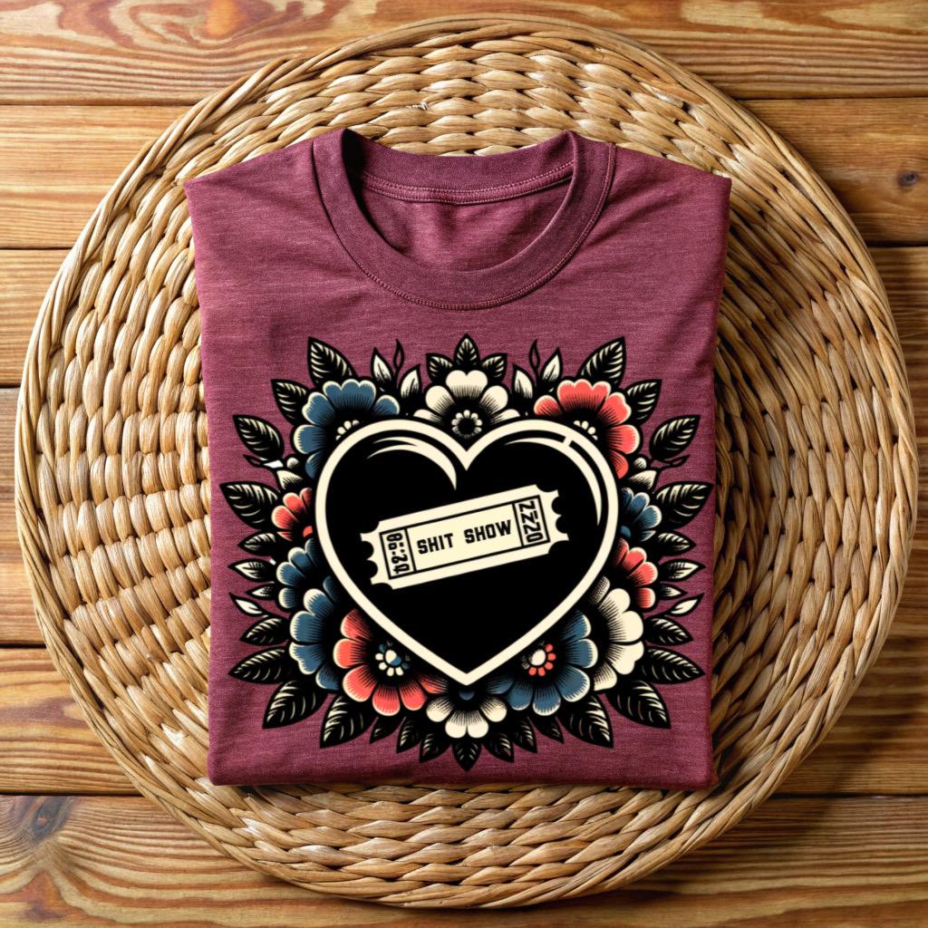 Maroon unisex t-shirt with ‘Shit Show’ ticket inside black heart, surrounded by vintage floral tattoo art