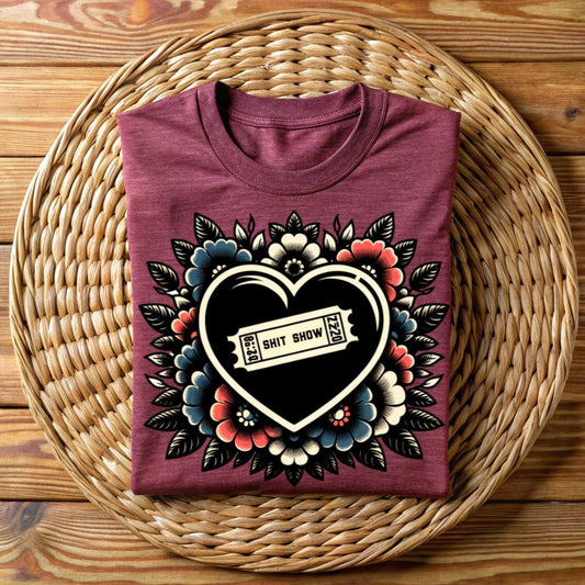 Maroon unisex t-shirt with ‘Shit Show’ ticket inside black heart, surrounded by vintage floral tattoo art