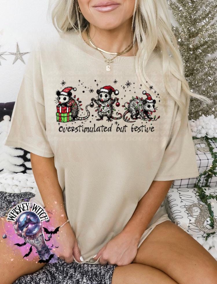 Black unisex sweatshirt with ‘Overstimulated but Festive’ skeleton Christmas graphic, snowflake accents, modeled indoors