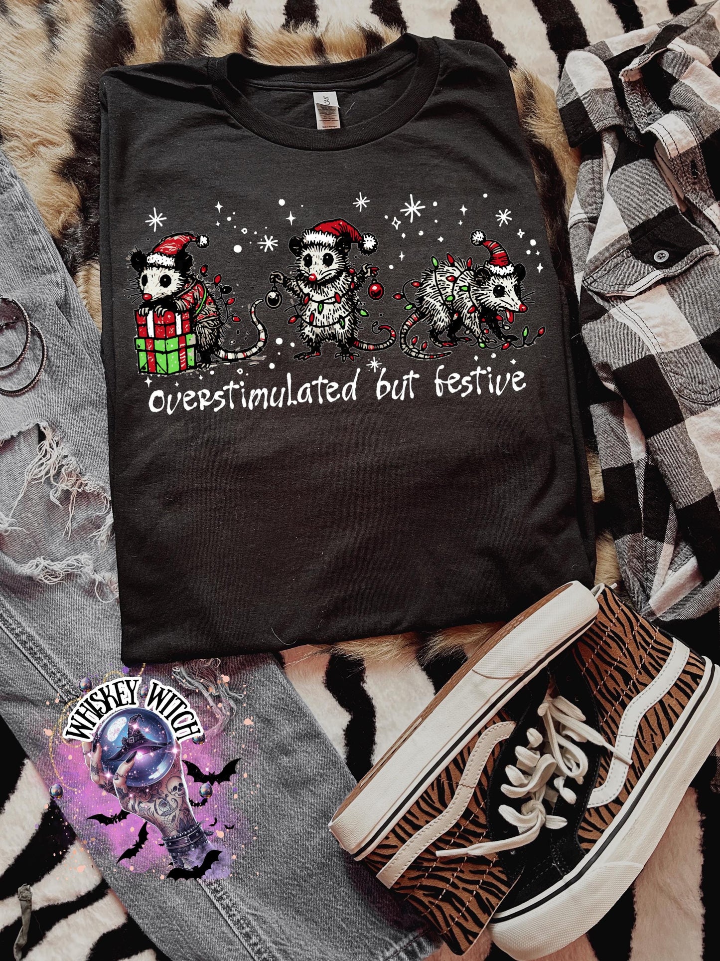 Black unisex sweatshirt with ‘Overstimulated but Festive’ skeleton Christmas graphic, snowflake accents, modeled indoors
