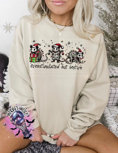 Black unisex sweatshirt with ‘Overstimulated but Festive’ skeleton Christmas graphic, snowflake accents, modeled indoors