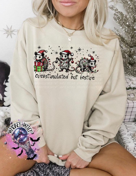 Black unisex sweatshirt with ‘Overstimulated but Festive’ skeleton Christmas graphic, snowflake accents, modeled indoors