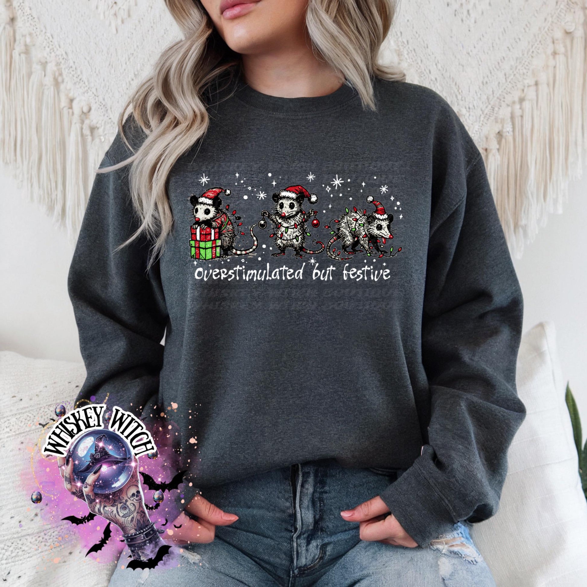 Black unisex sweatshirt with ‘Overstimulated but Festive’ skeleton Christmas graphic, snowflake accents, modeled indoors