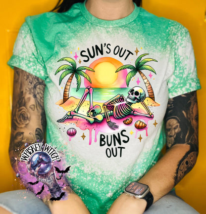 A free t-shirt with a graphic of a skeleton relaxing on a beach with palm trees and the text "Sun's Out Buns Out." The shirt has a bleached effect.
