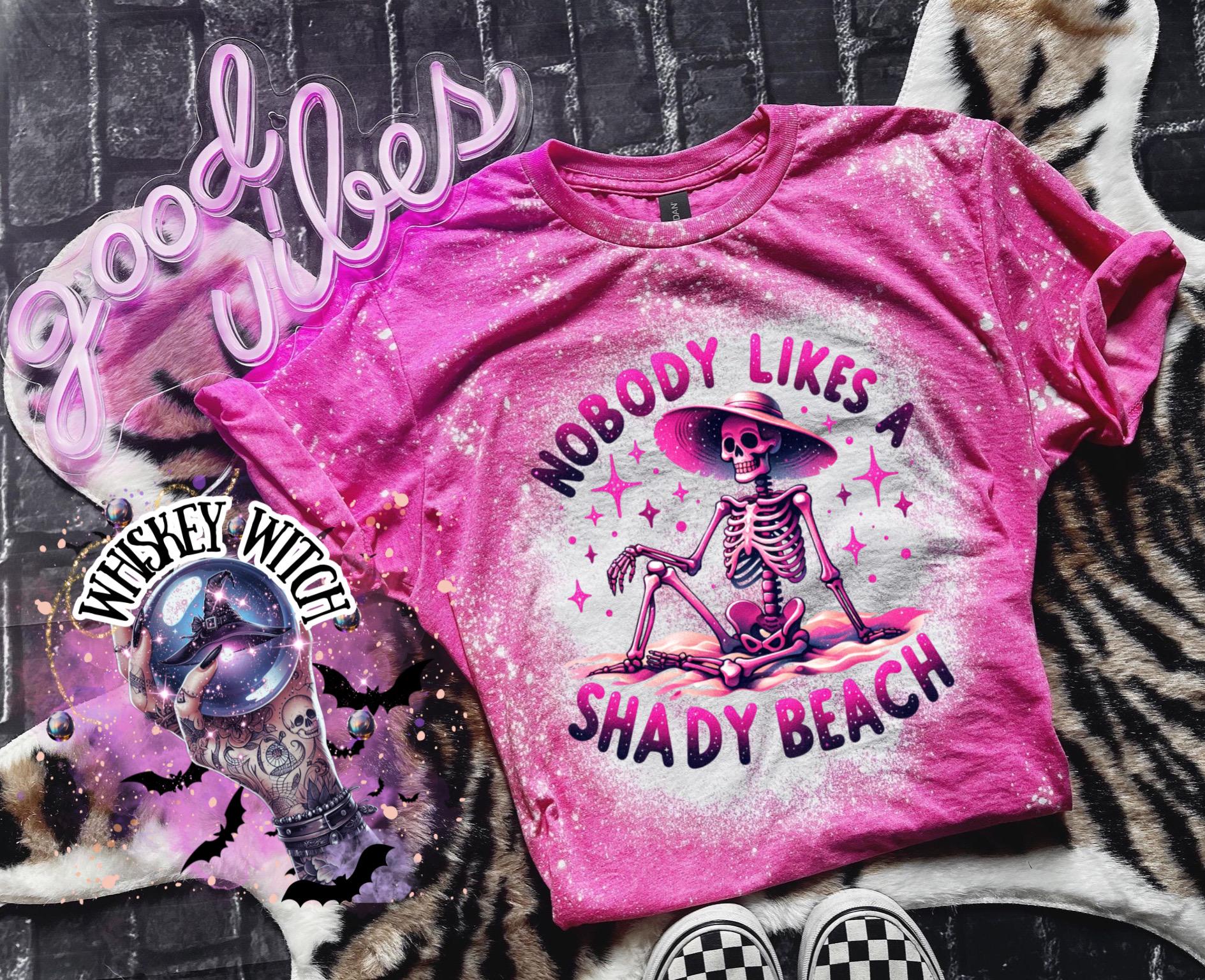 A pink t-shirt with a bleached design featuring a skeleton wearing a hat, the text "Nobody Likes a Shady Beach," and star graphics. The shirt is paired with black and white checkered sneakers.
