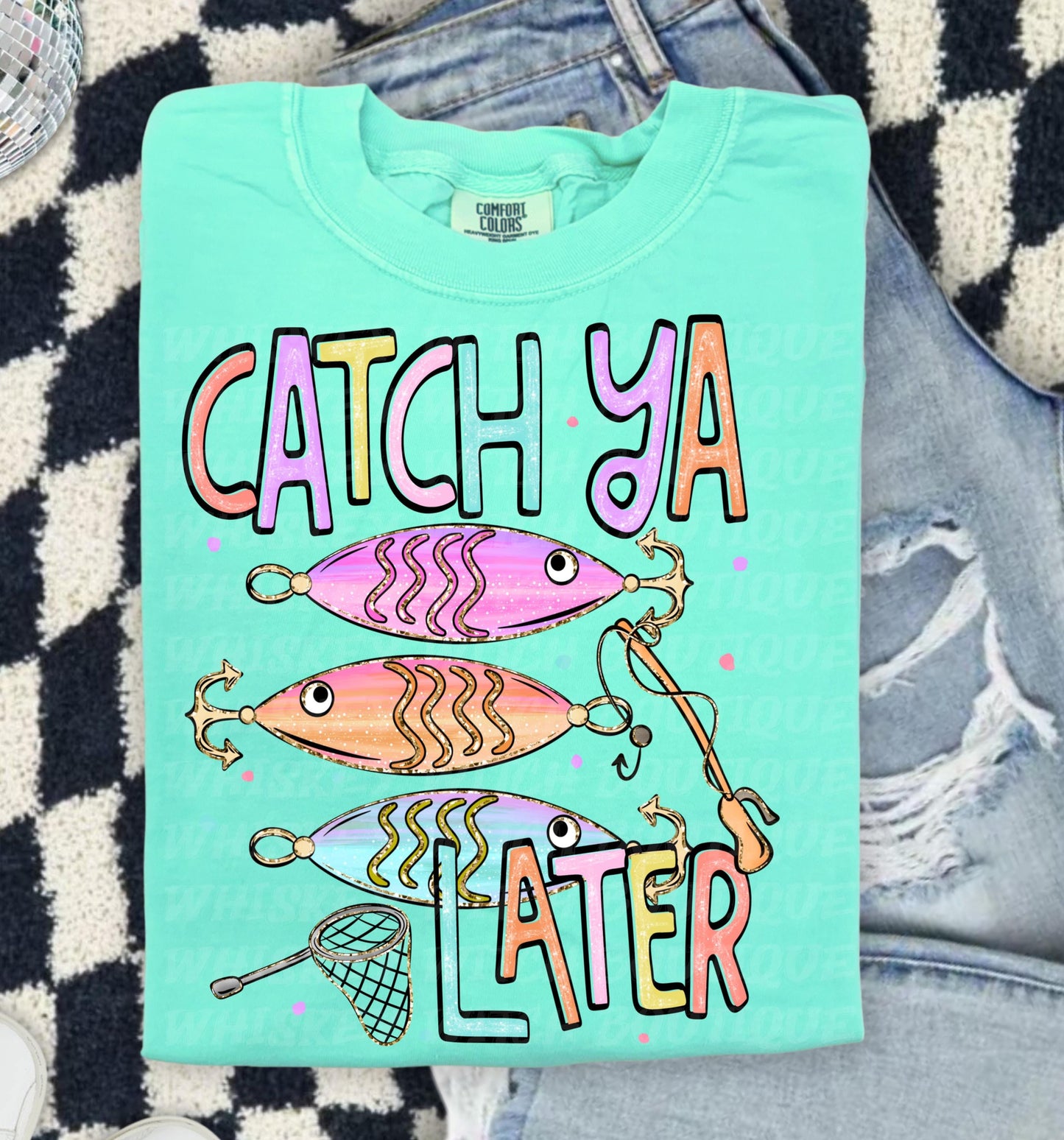 Cute lake day graphic tee with Catch Ya Later text, fishing lures, and a small fishing net design.