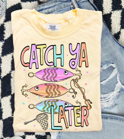 Cute lake day graphic tee with Catch Ya Later text, fishing lures, and a small fishing net design.