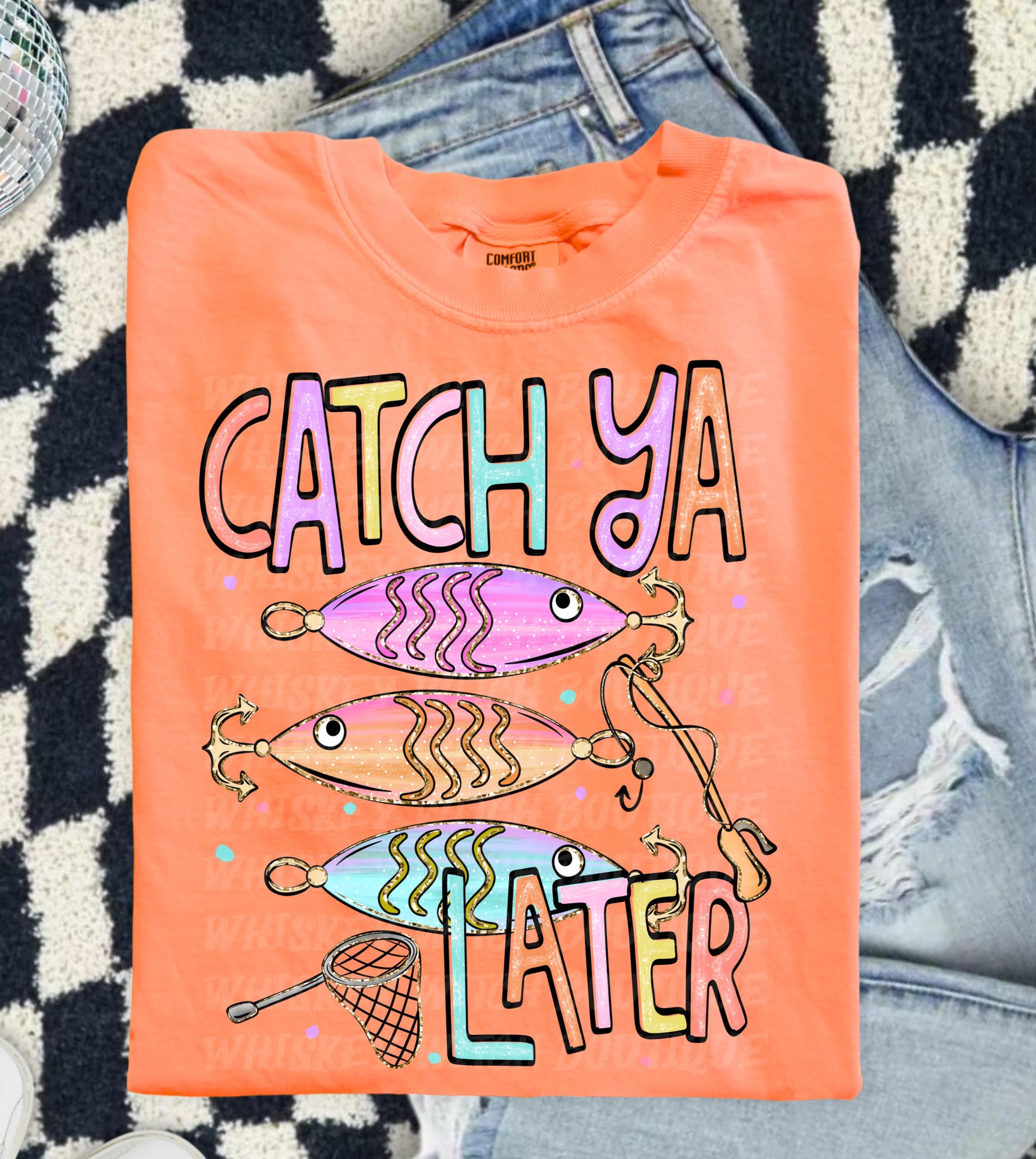 Cute lake day graphic tee with Catch Ya Later text, fishing lures, and a small fishing net design.