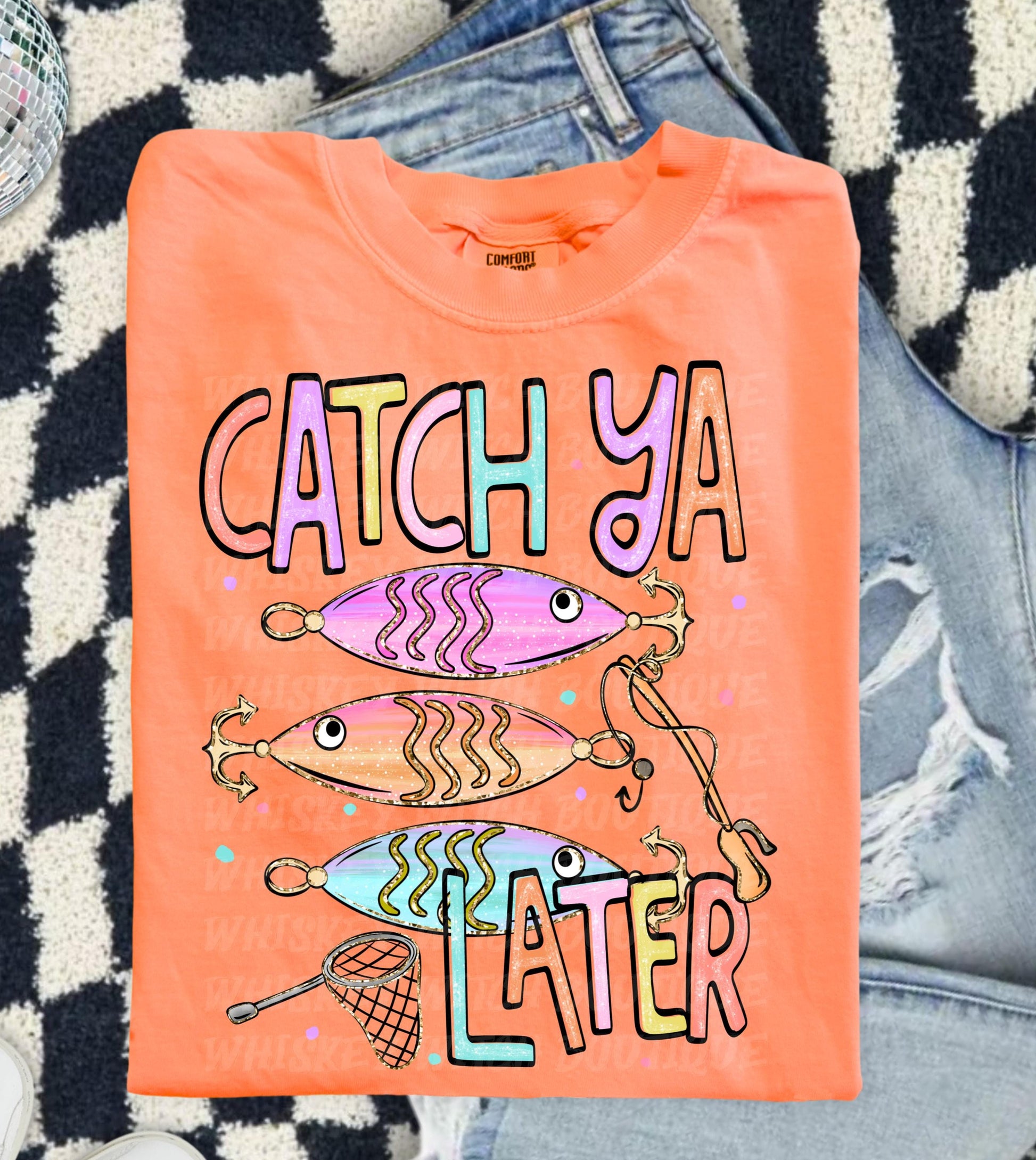 Cute lake day graphic tee with Catch Ya Later text, fishing lures, and a small fishing net design.