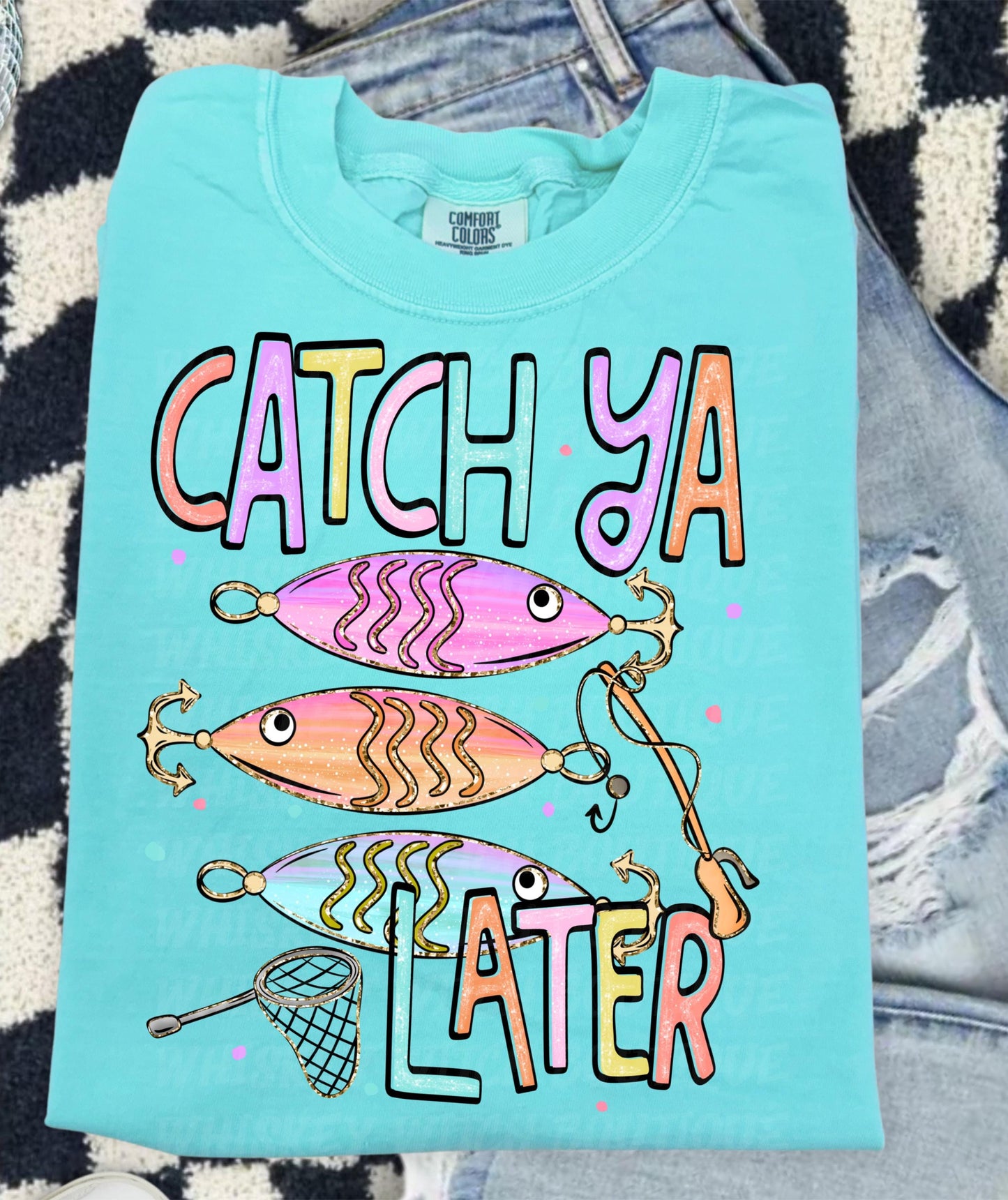 Cute lake day graphic tee with Catch Ya Later text, fishing lures, and a small fishing net design.