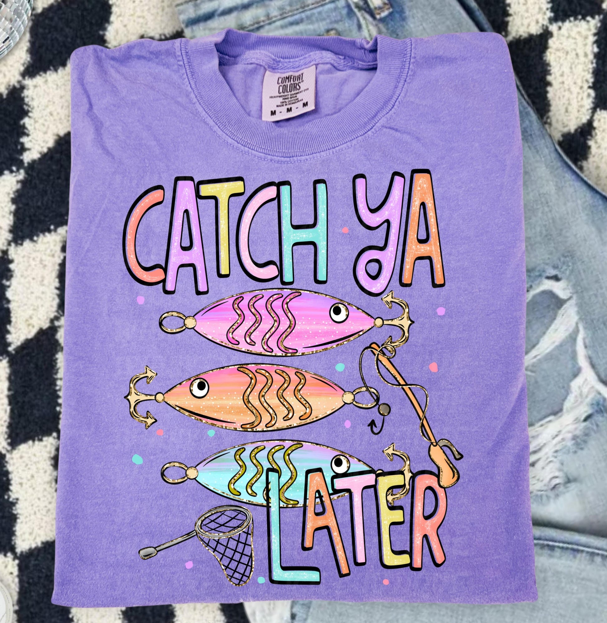 Cute lake day graphic tee with Catch Ya Later text, fishing lures, and a small fishing net design.